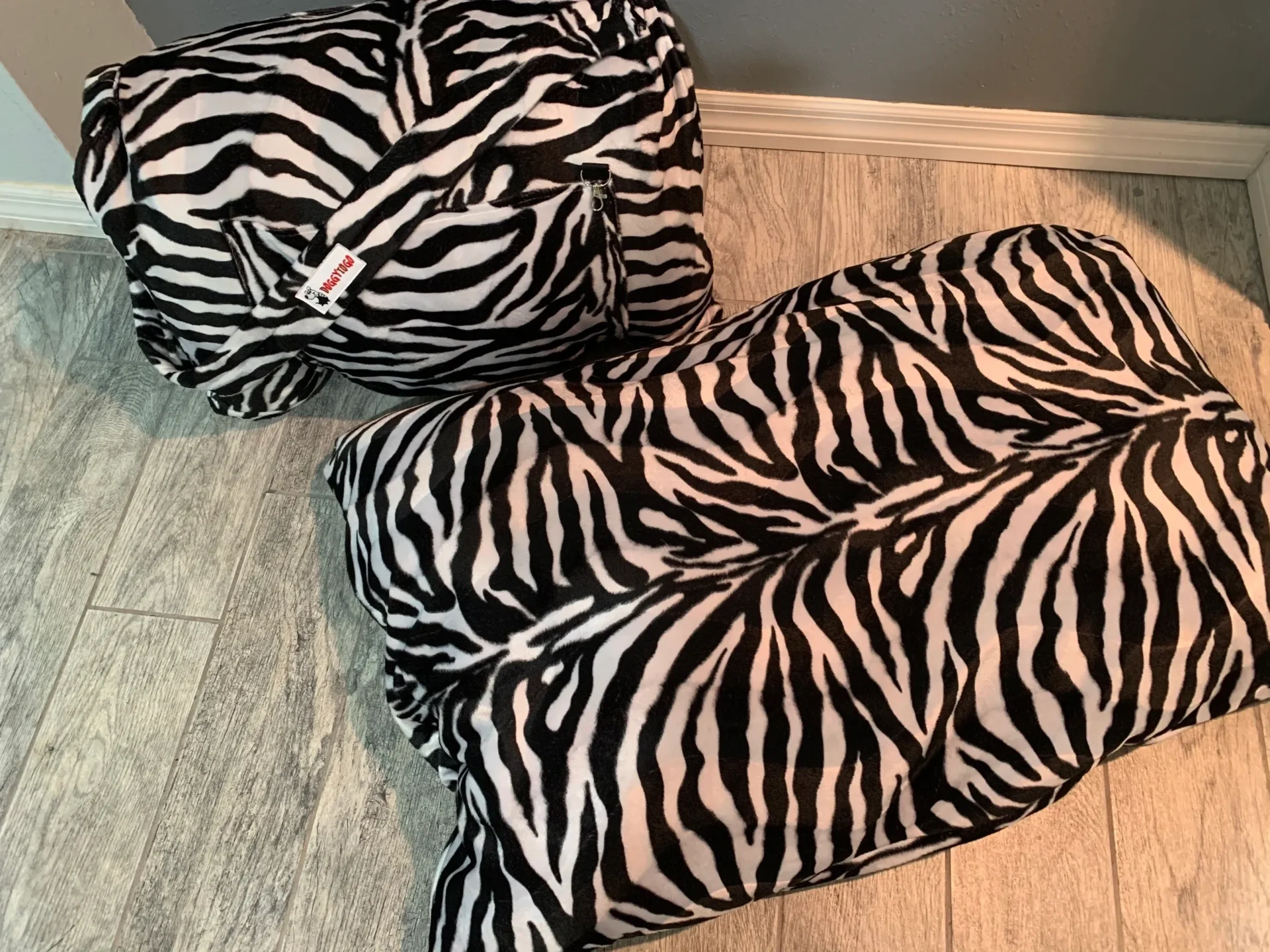 Two dog bed bags with white and black patterns lying down on the floor