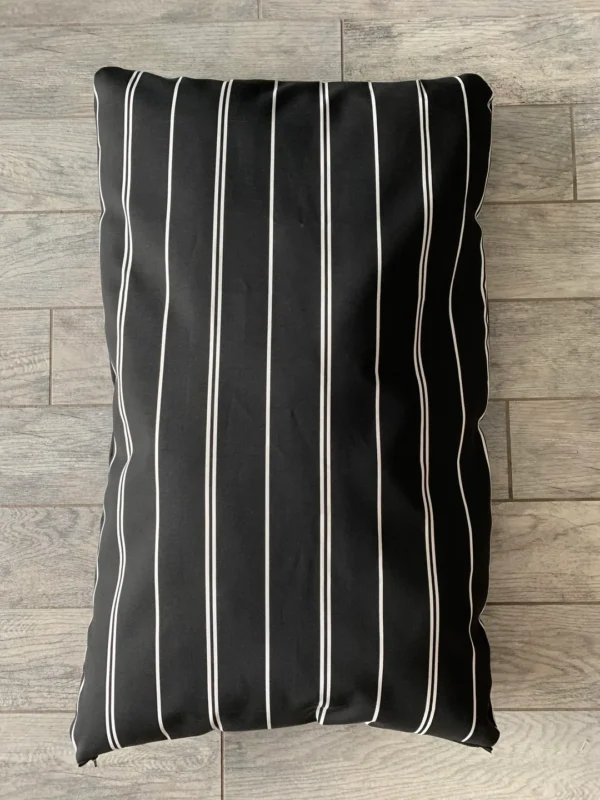 A black dog bed bag with stripes on the floor