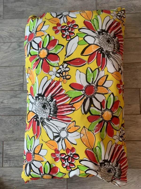 Yellow colored dog bed bag with designs of flowers printed on it lying on the floor