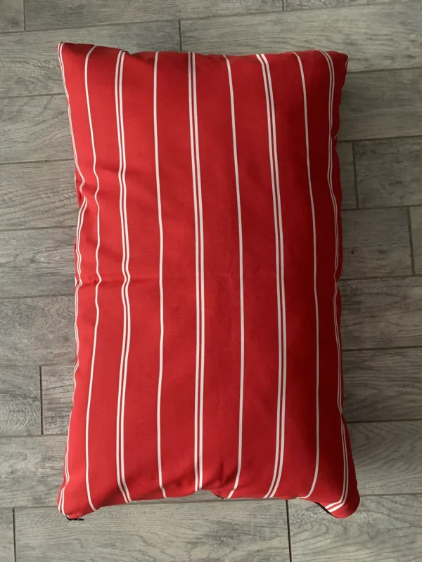 A red color dog bed bag on the floor