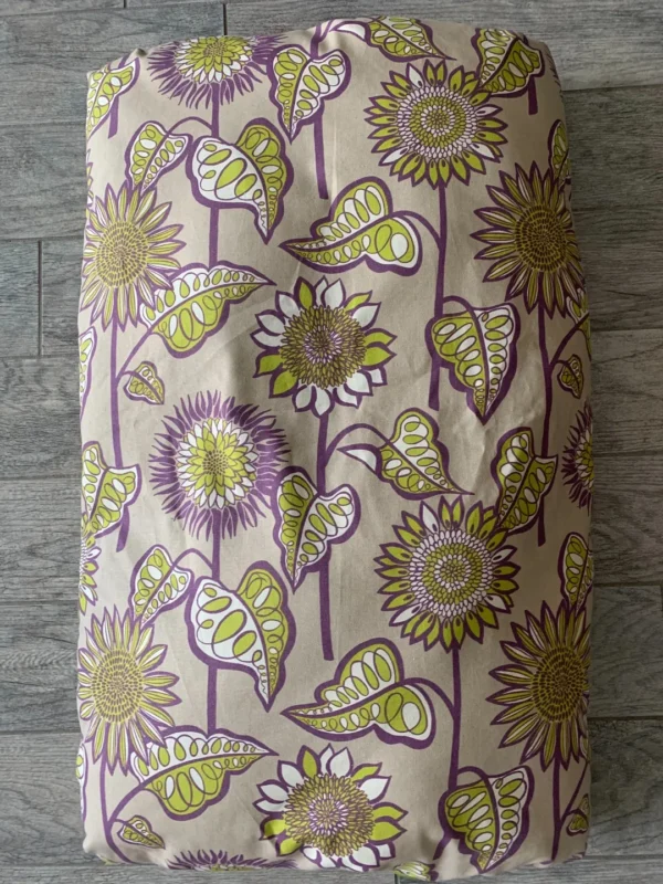 A small photograph of a light brownish color dog bed bag with violet and green flower designs
