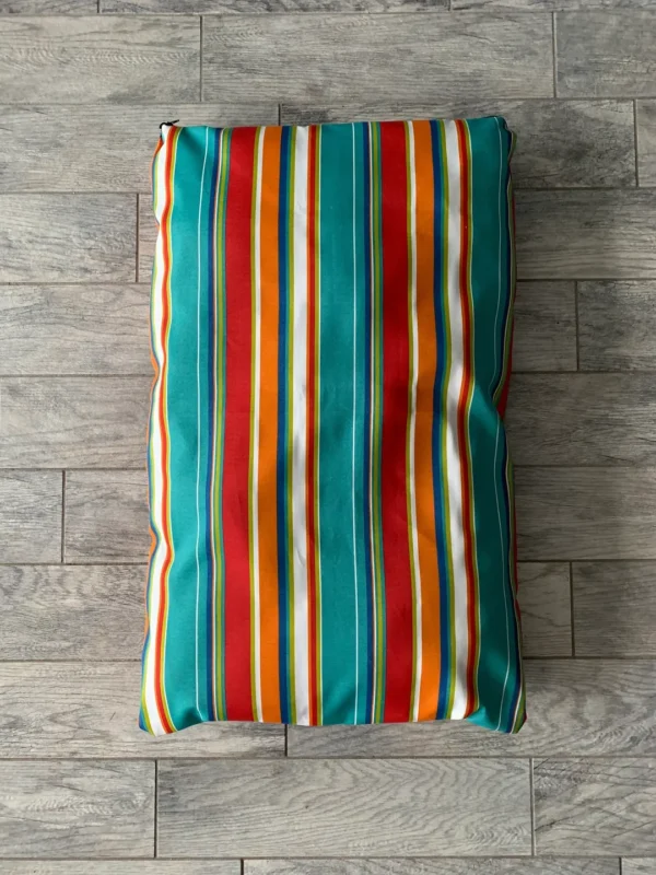 A multicolored dog bed bag lying on the floor