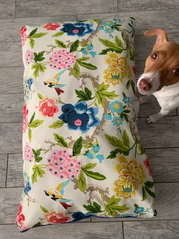 A small image of a white dog bed bag with a dog standing right beside it